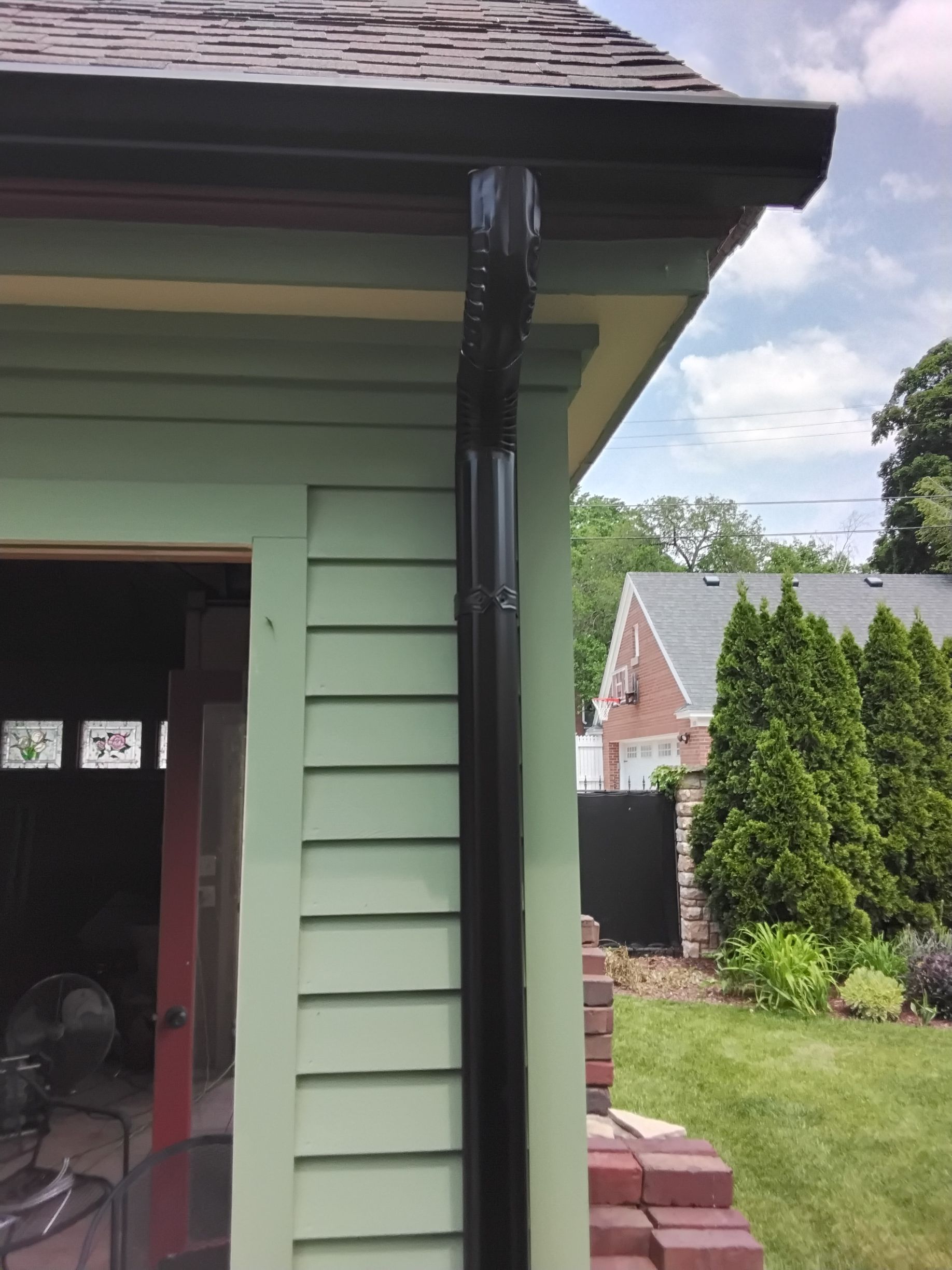 A green house with a black gutter on the side