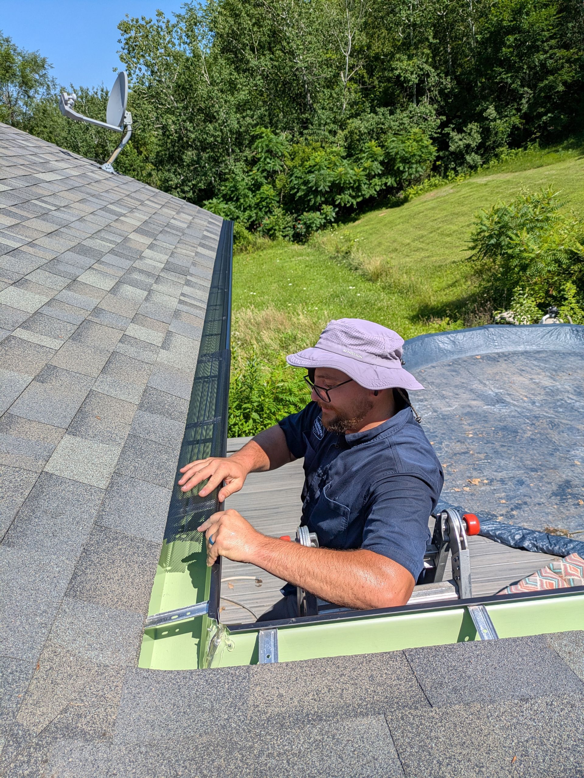 A man is sitting on top of a ladder working on a roof.