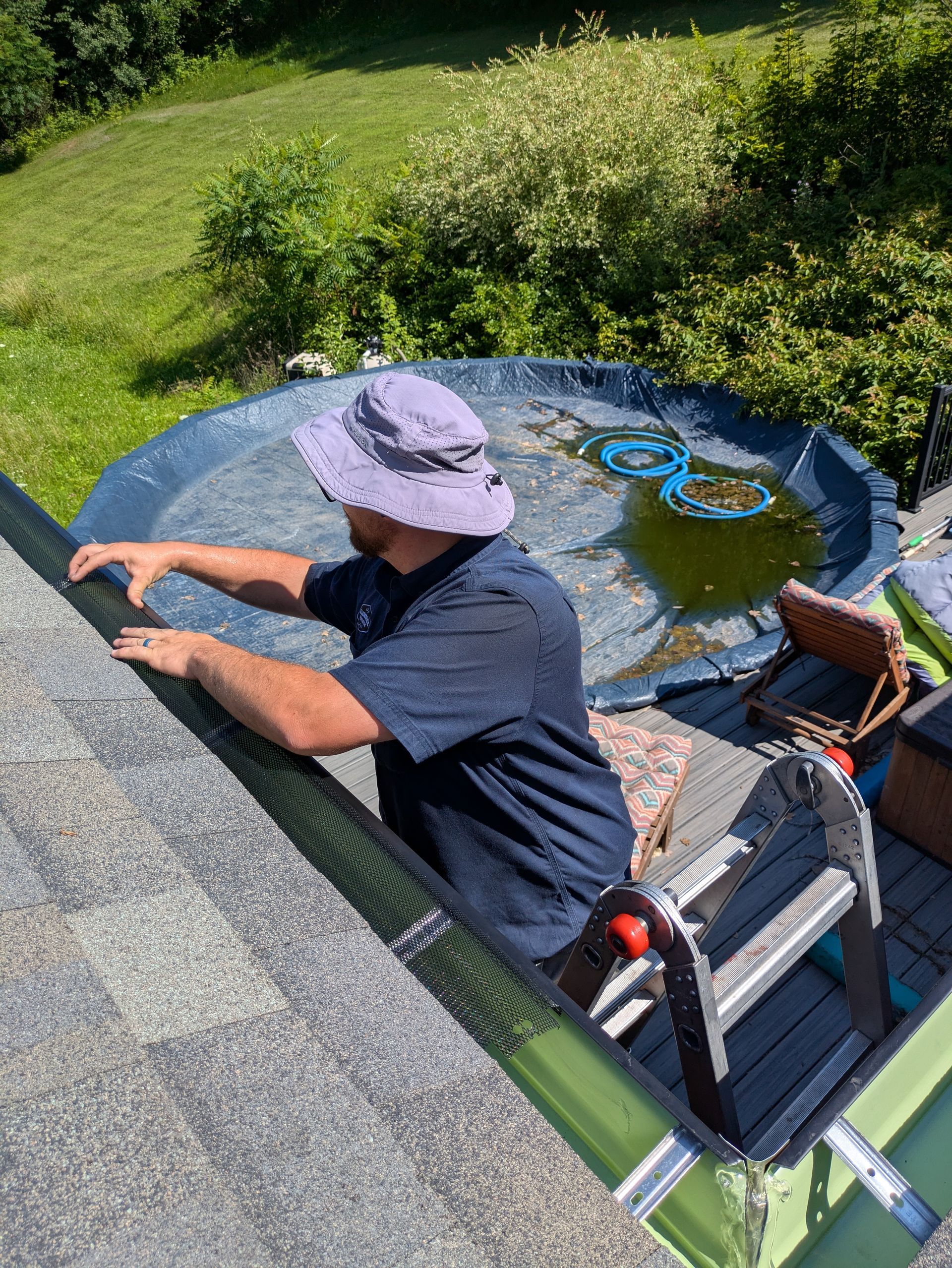 A man is standing on top of a roof next to a pool.