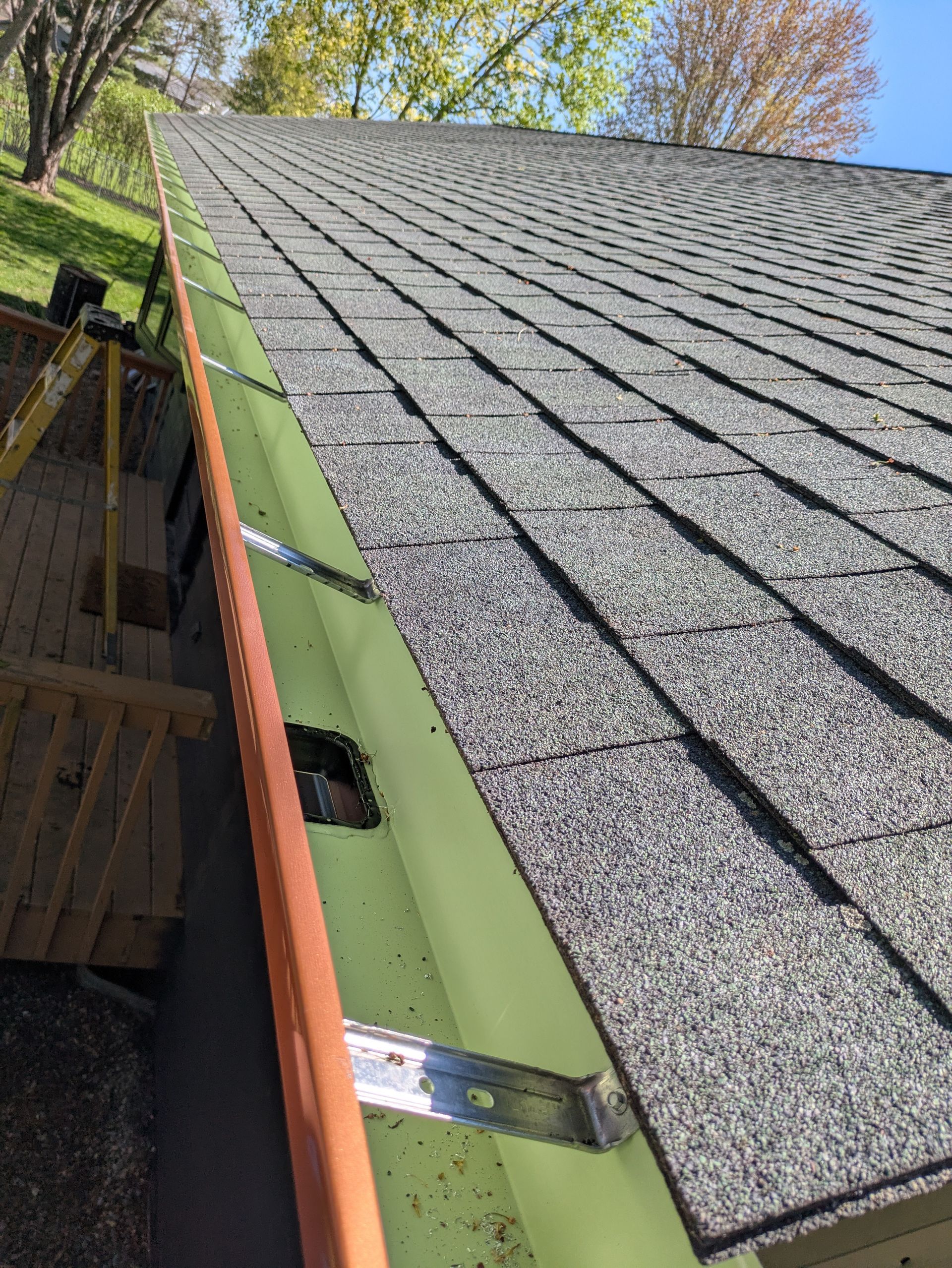 A close up of a roof with a green gutter on it.