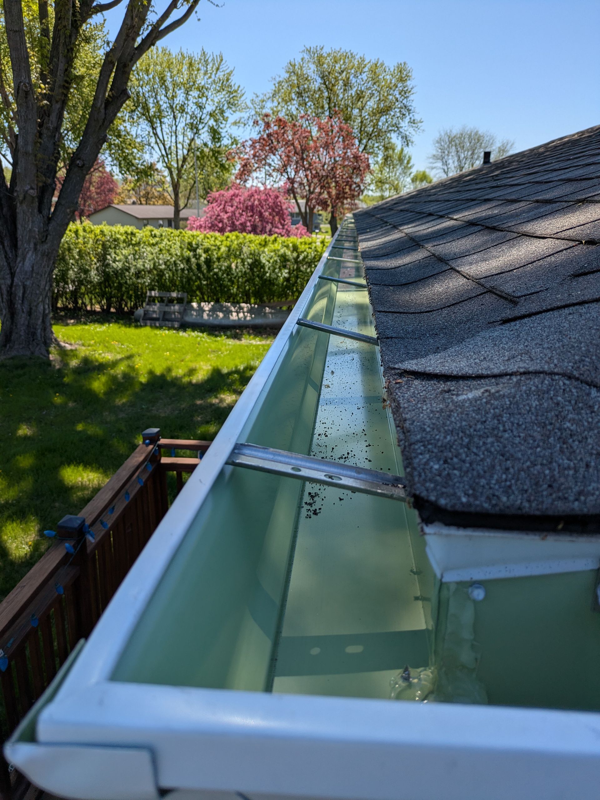 A white gutter is attached to the roof of a house.