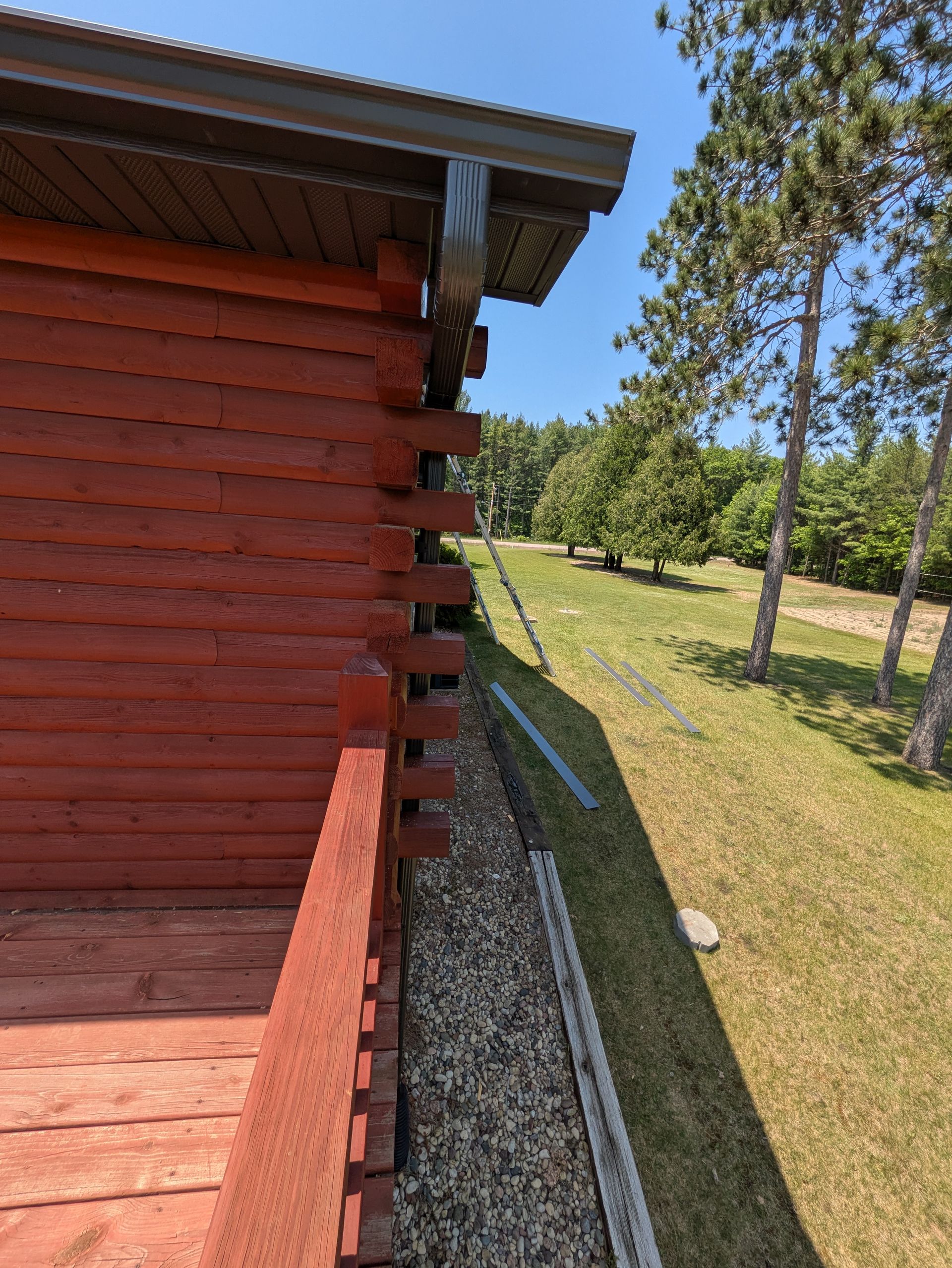 A red log cabin is sitting in the middle of a grassy field.