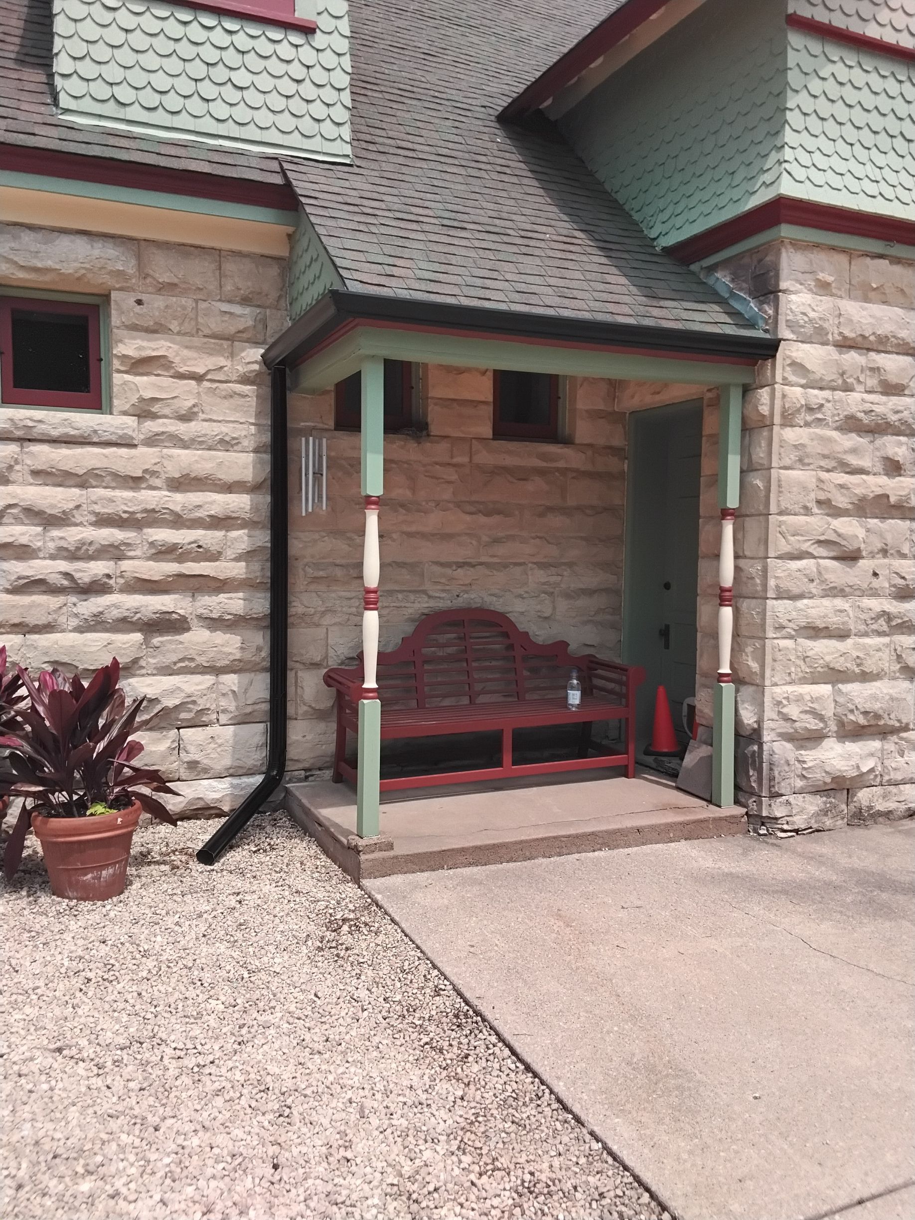 A brick building with a porch and a bench on it