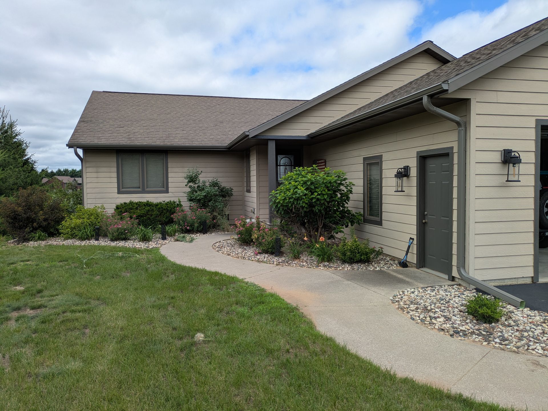 A house with a walkway leading to it and a lawn in front of it.