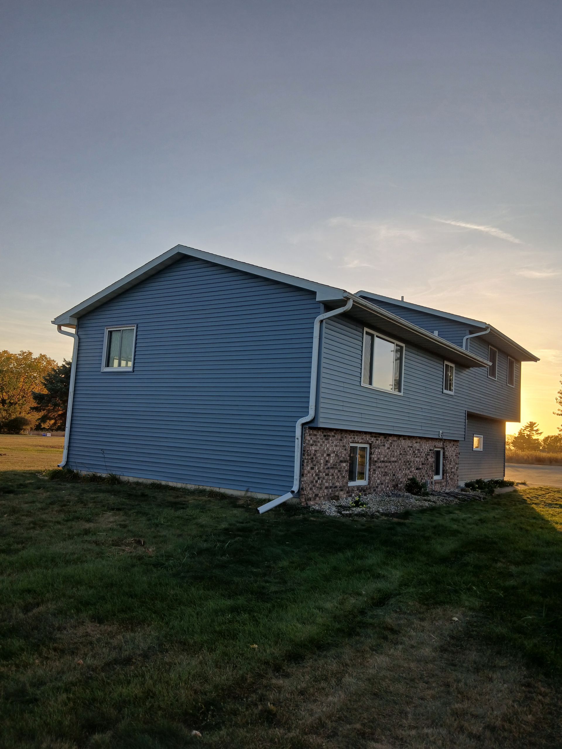 A blue house is sitting on top of a lush green field.