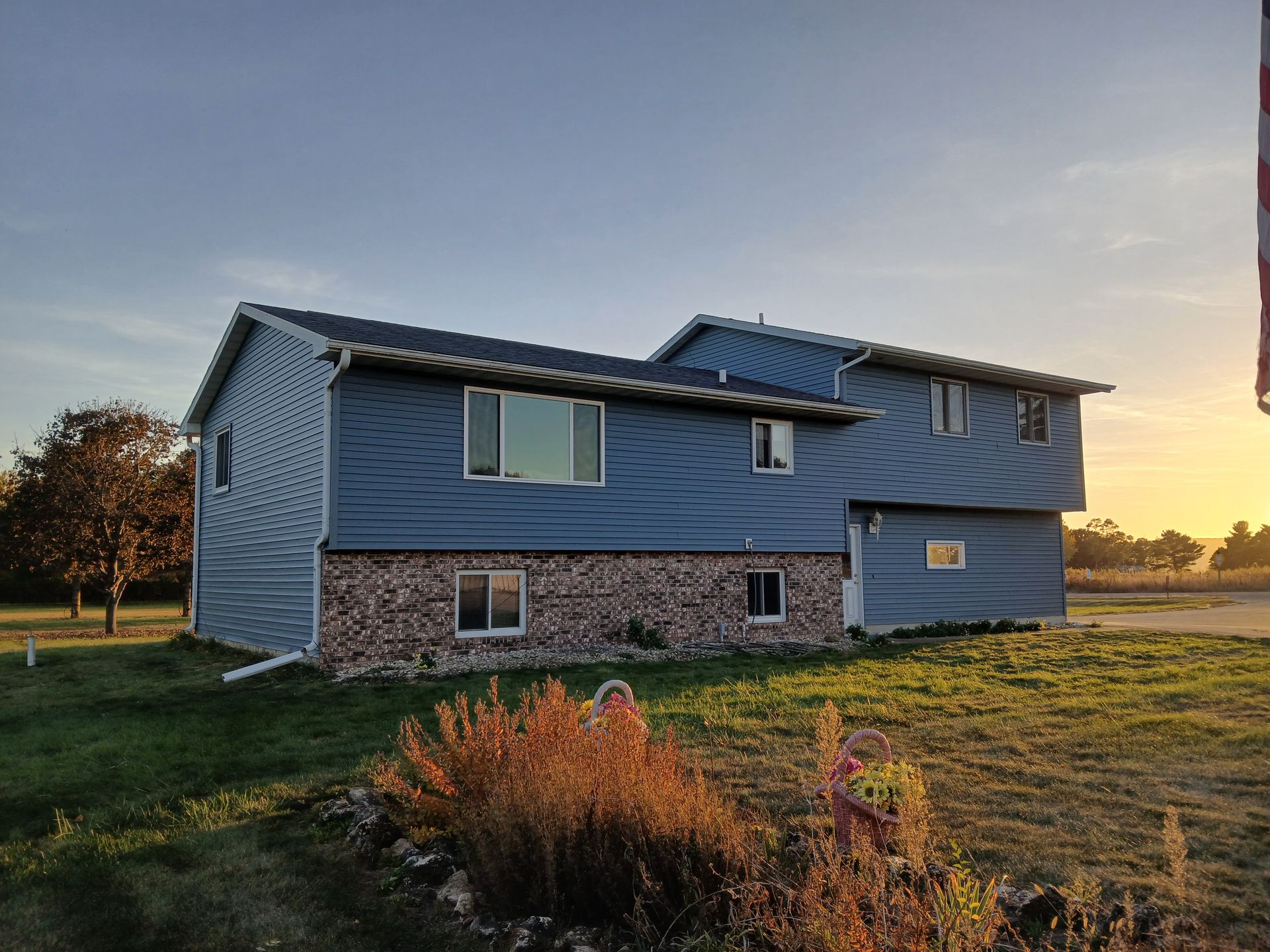 A large house with a lot of windows is sitting on top of a lush green field.