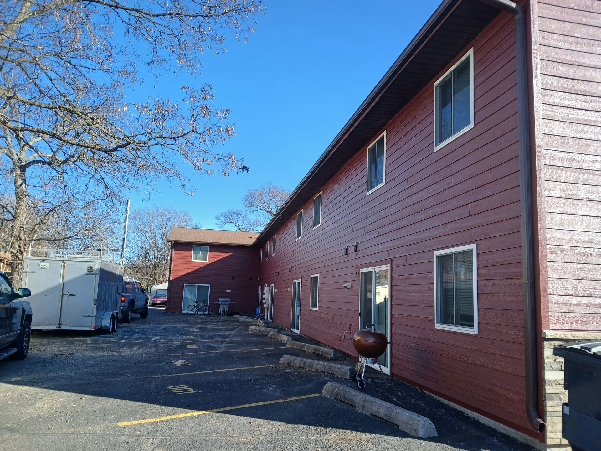 A red apartment building with a barbecue grill in front of it