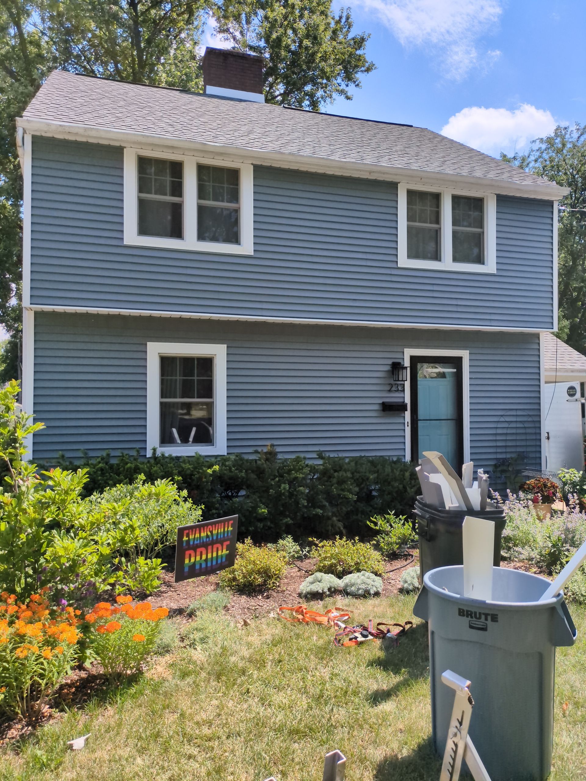 A house with a trash can in front of it.
