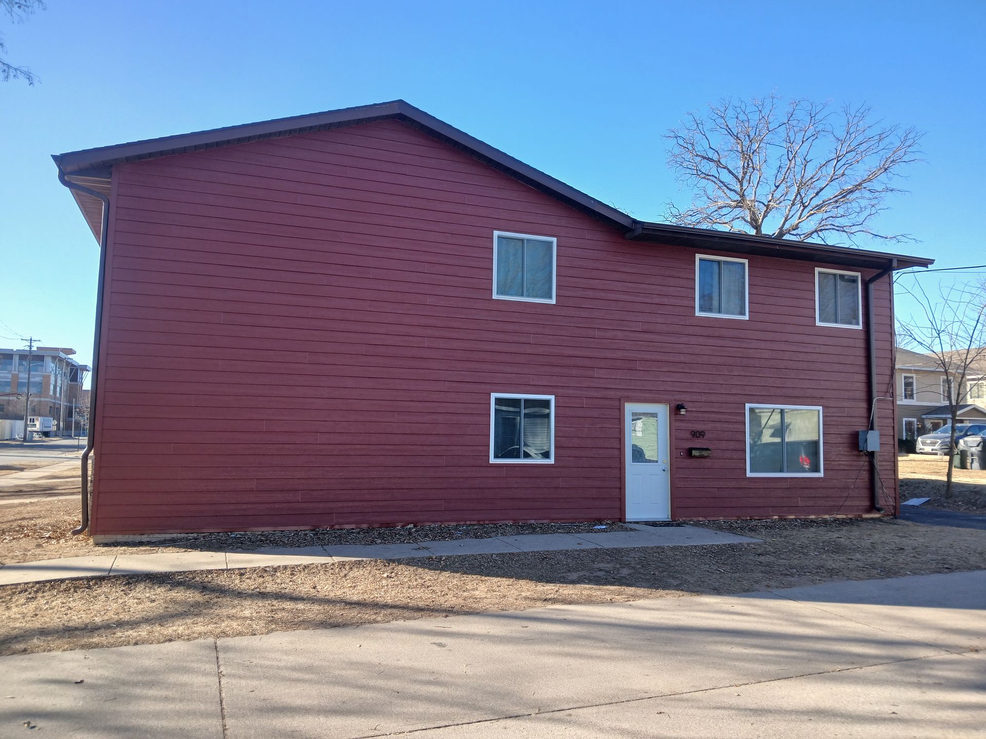A red apartment building with a white door and windows.