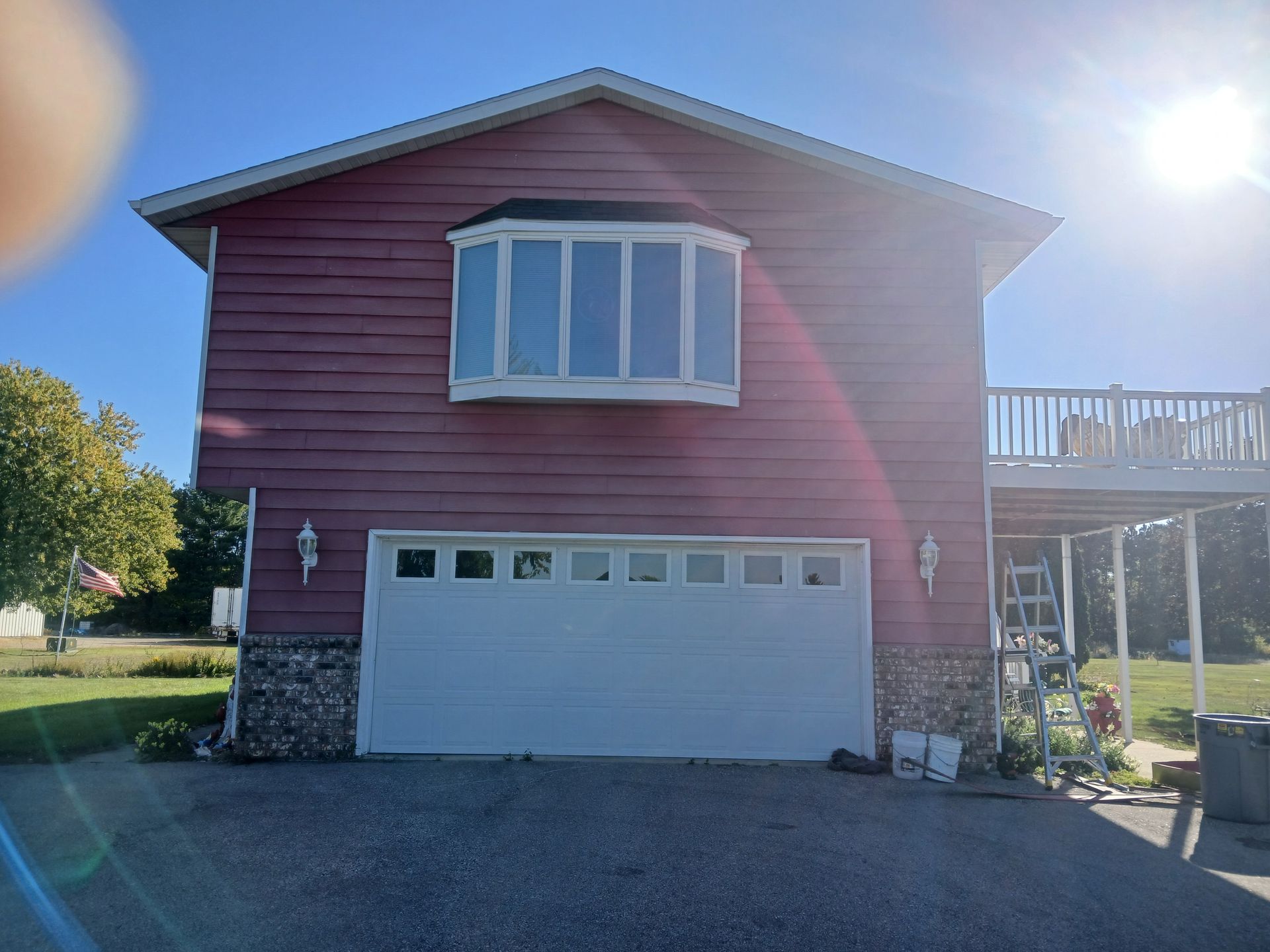 A red house with a white garage door and a balcony.