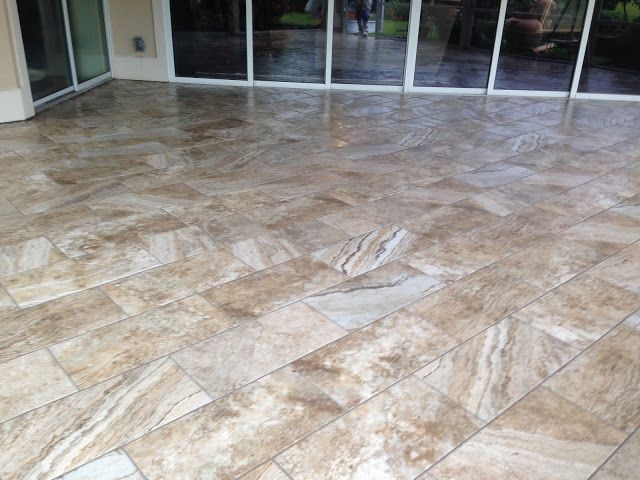 Beige tiled outdoor patio with glass sliding doors reflecting the environment.