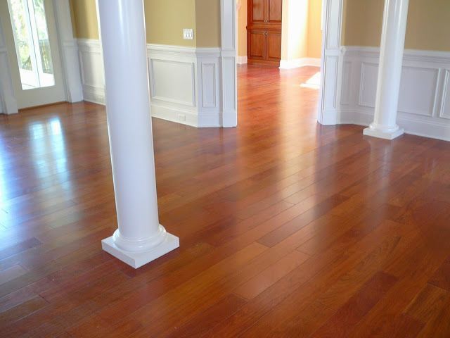 Polished wood floor in a room with white columns, baseboards, and walls painted yellow.
