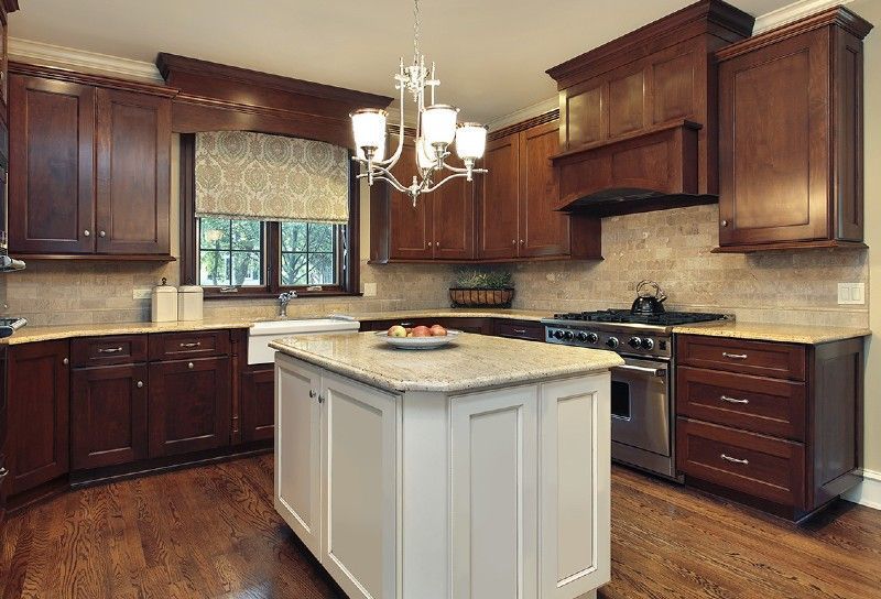 Kitchen with dark brown cabinets, white island, stainless steel appliances, and wood floor.