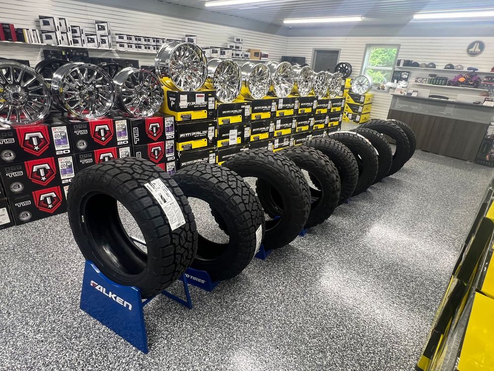Tire shop display with rows of off-road tires and wheels in a showroom