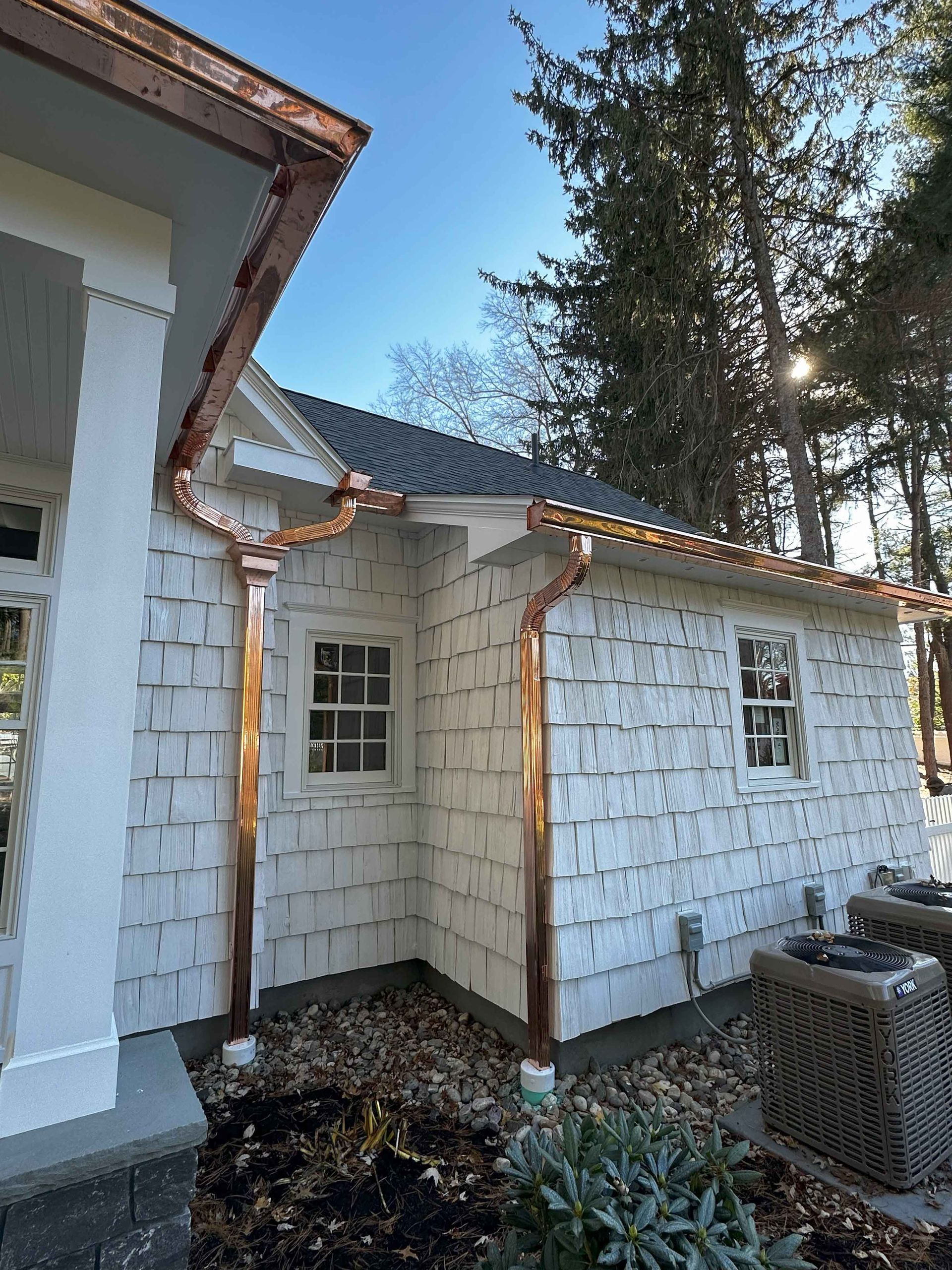 A white house with a copper gutter on the side of it.