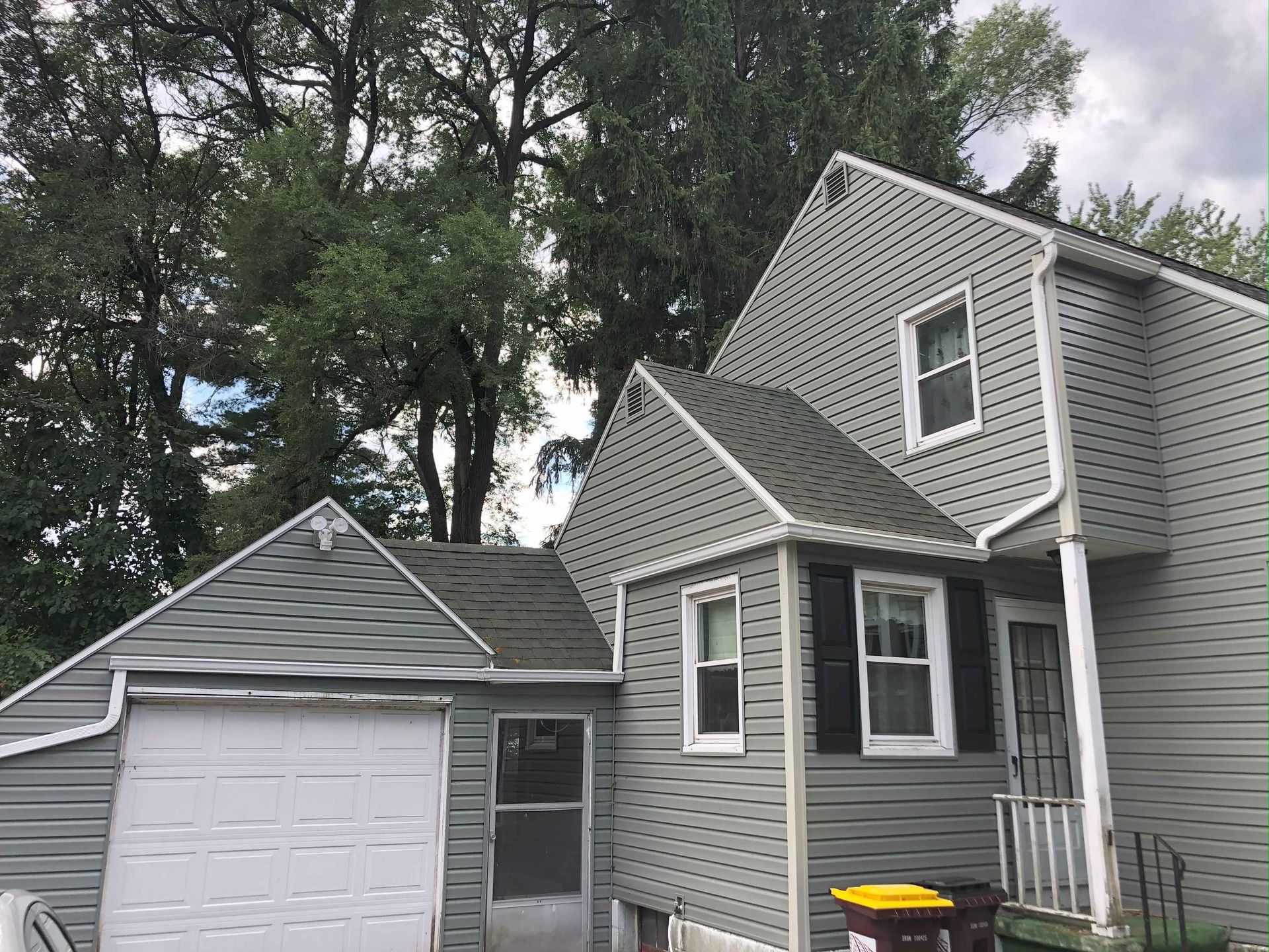 The front of a house with a garage and trees in the background