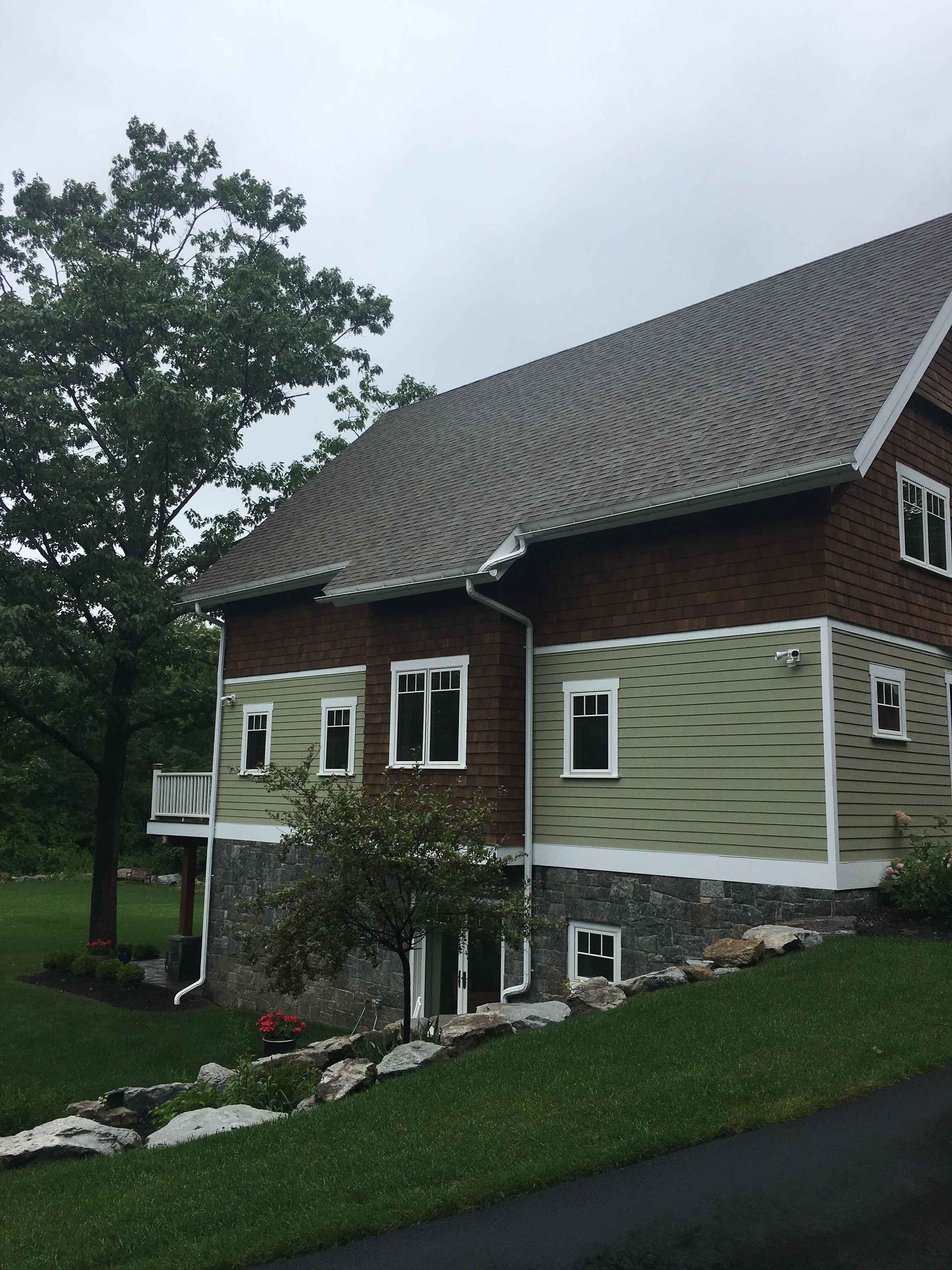 A brown house with green siding and a gray roof