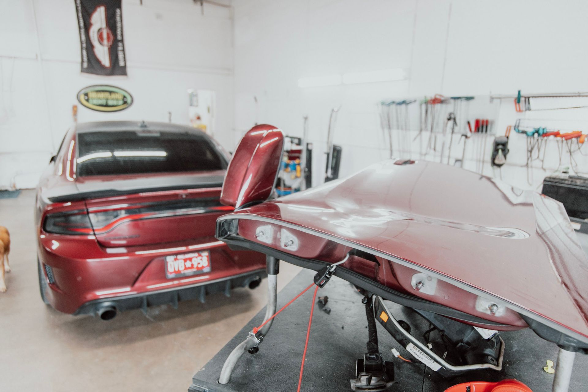 Red Dodge Charger in a shop, with the trunk lid open on a stand.