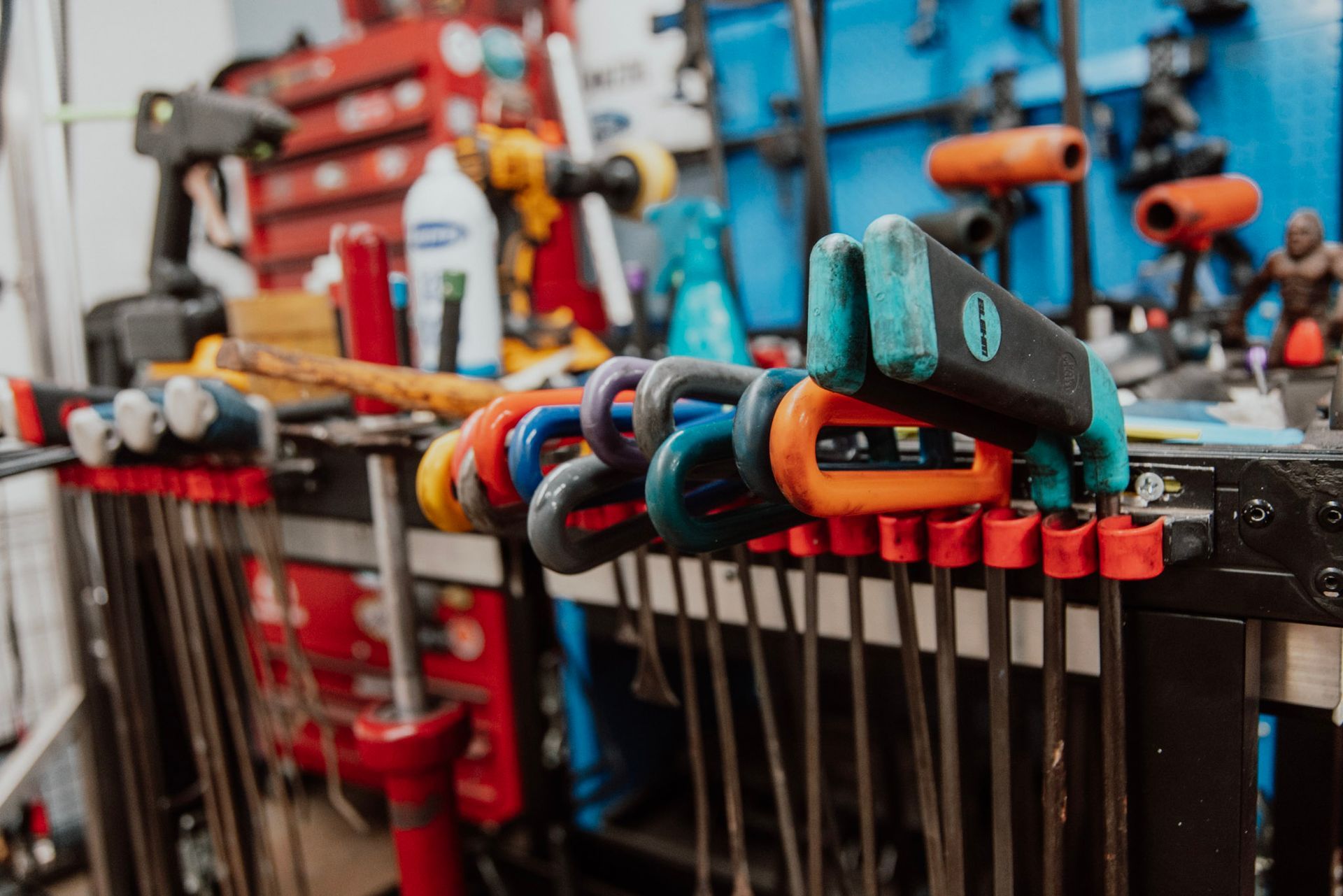 Close-up of a workshop tool rack with colorful clamps hanging on it.