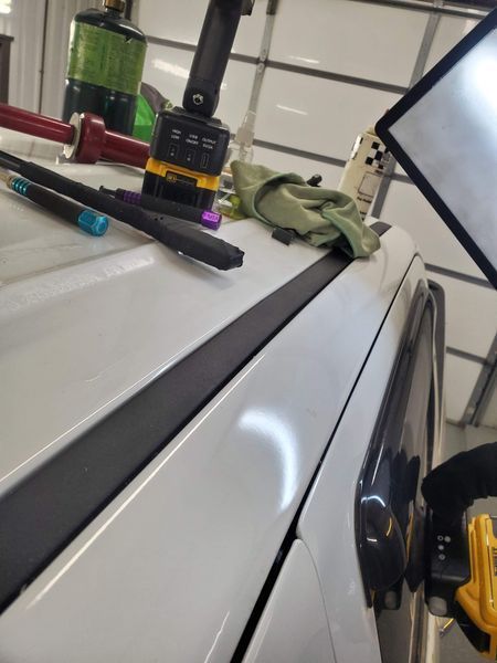 White car with dent repair tools on roof, showing dent reflection.