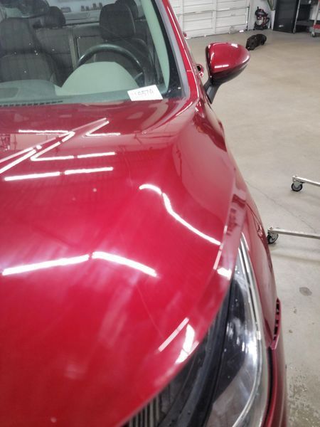 Red car front, showing hood and headlight in a garage.