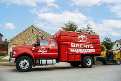 Red Brents Tree Service truck parked on a street in front of a house.