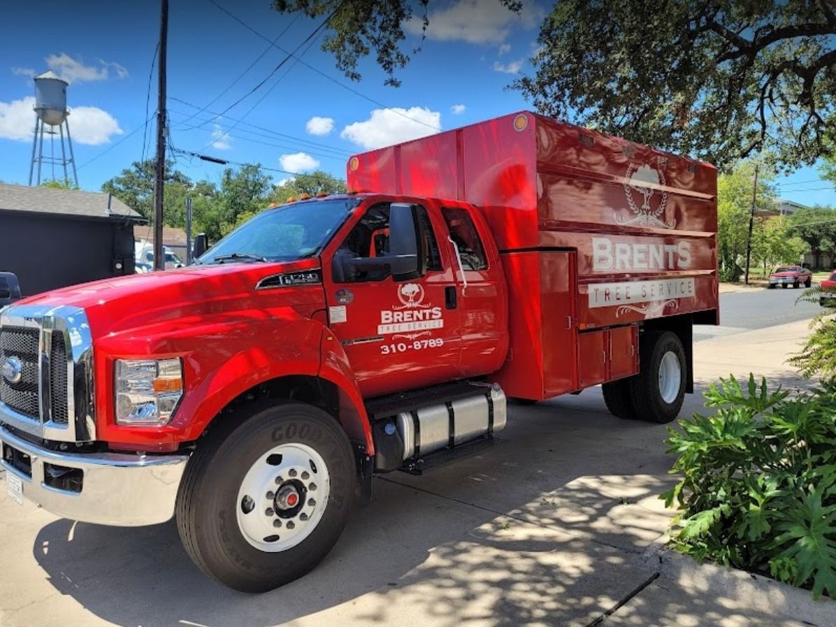 Red Brent's truck parked on the street.  The truck has a large cargo box and the company's name on the side.
