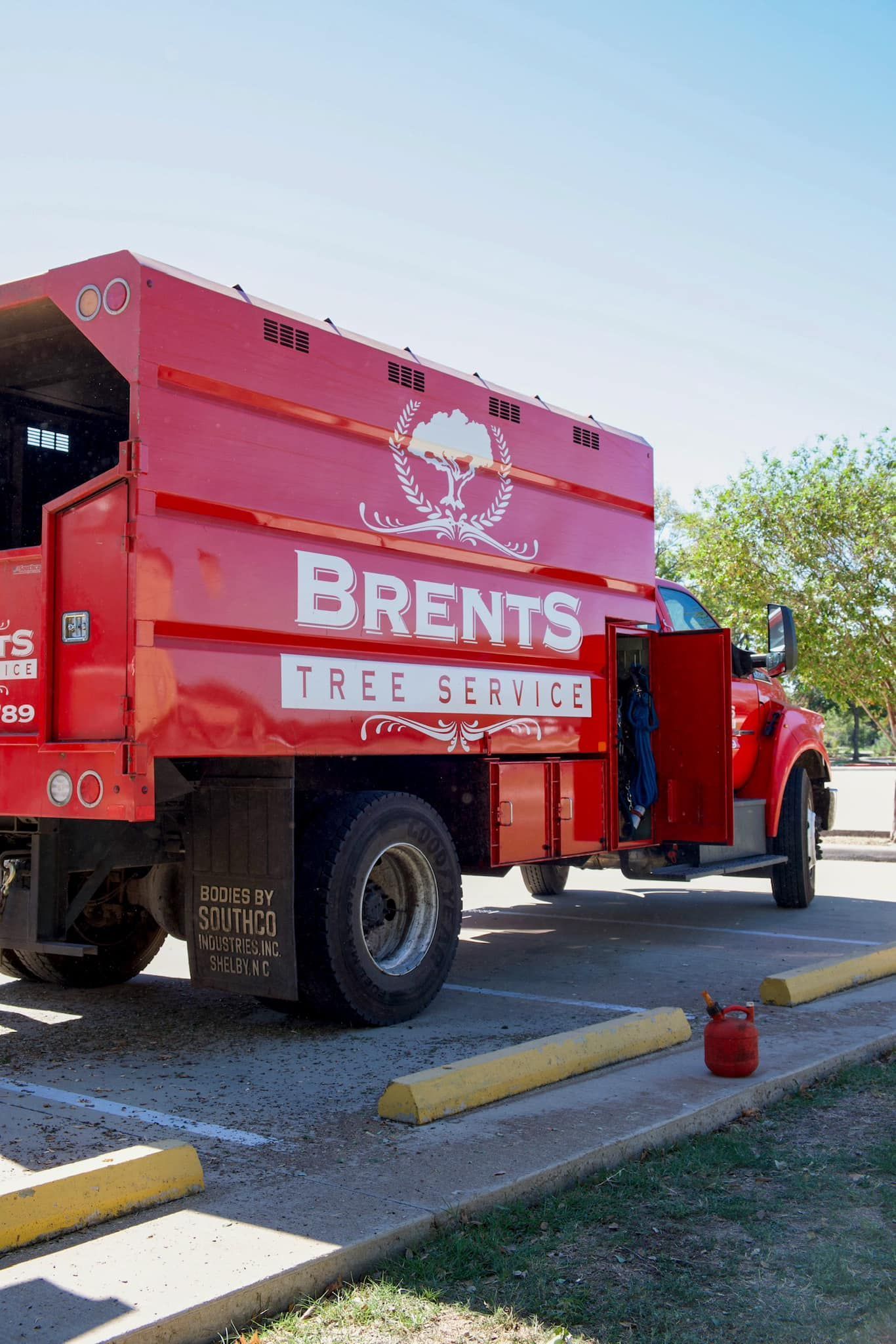 Red Brent's Tree Service truck parked on a paved area with the door open.
