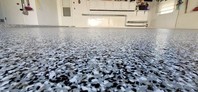 Low-angle view of a speckled gray floor in a bright, empty room with white cabinets