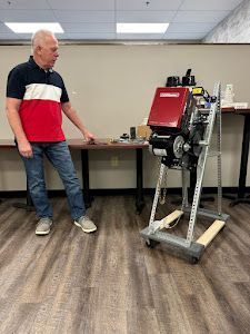 Man standing beside a red industrial machine in an office room