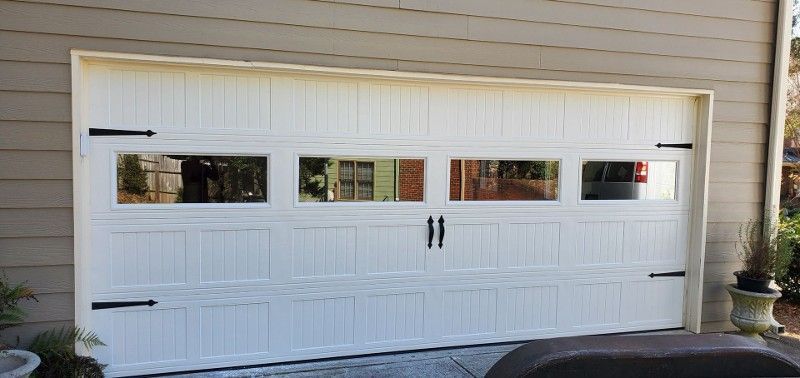 White double garage door on a beige house exterior with small windows and black handles