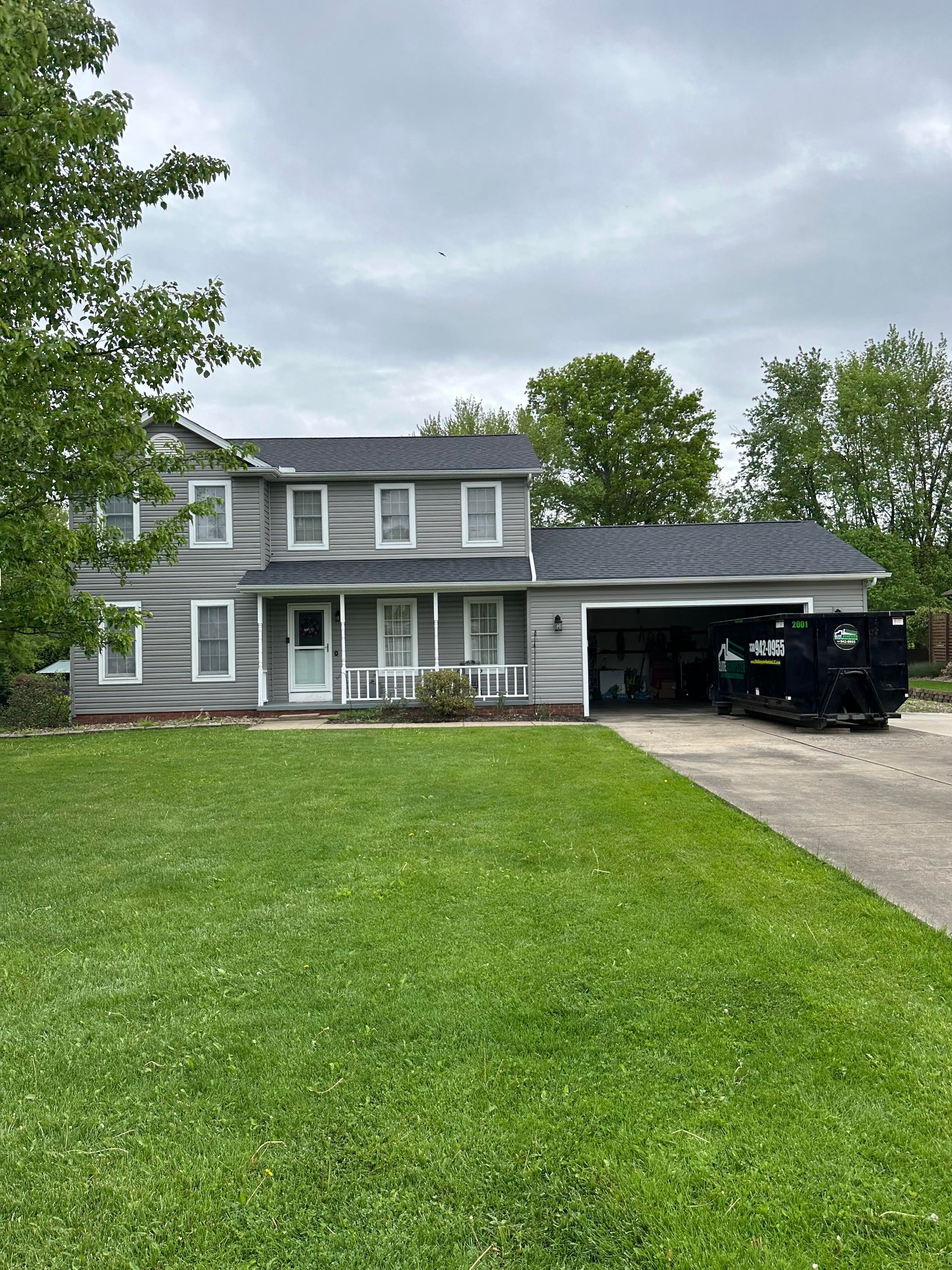 A large house with a large lawn and a dumpster in front of it.