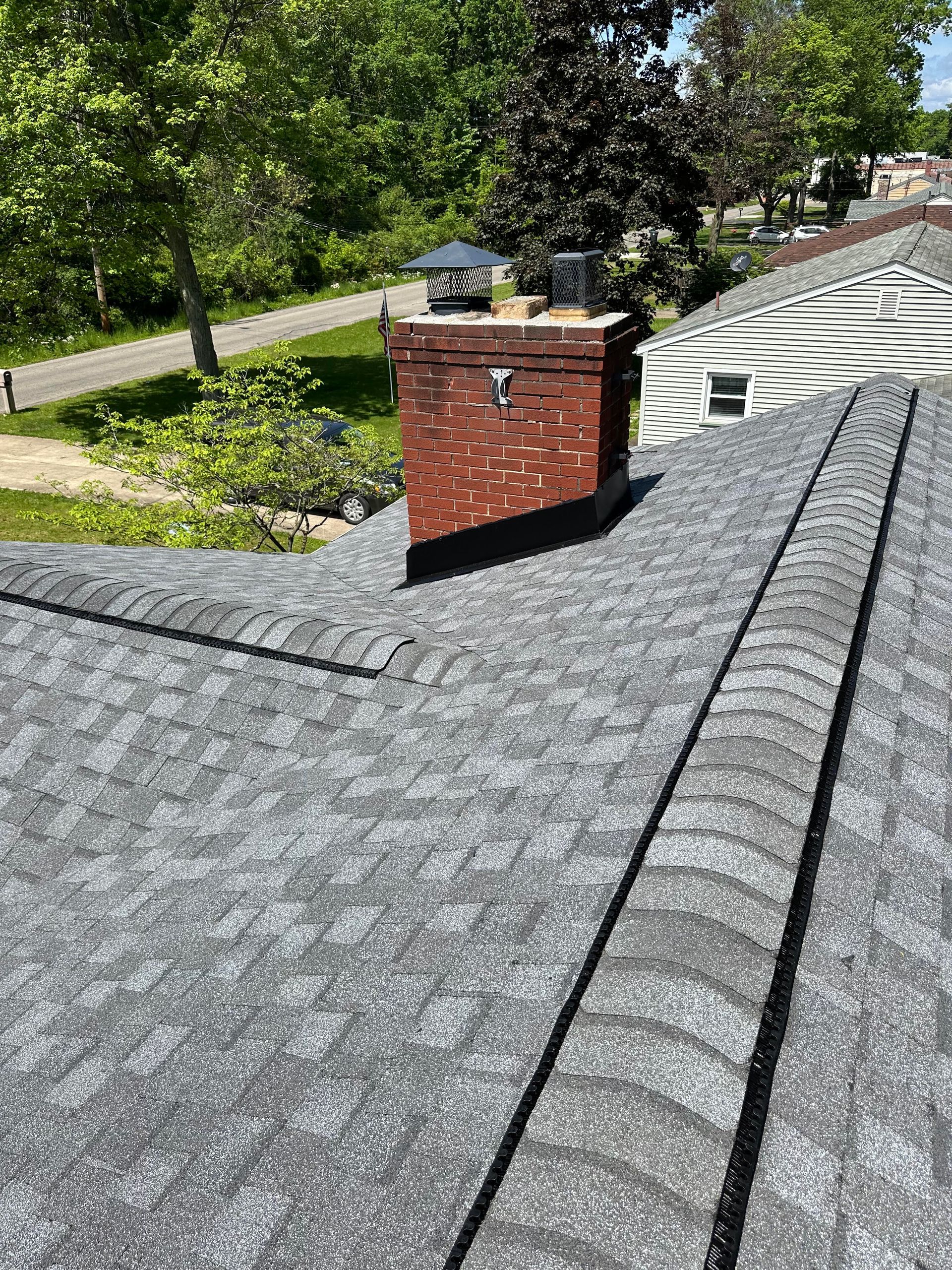 A roof with a chimney on top of it and trees in the background.