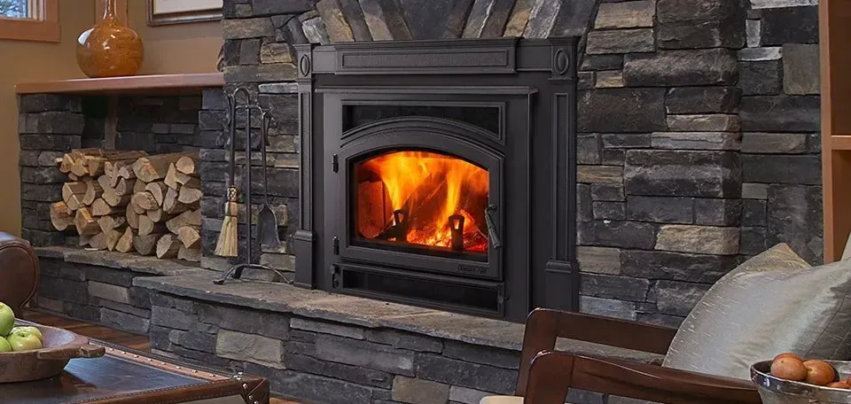 A fireplace with a roaring fire, surrounded by a stone mantel and a stack of firewood.