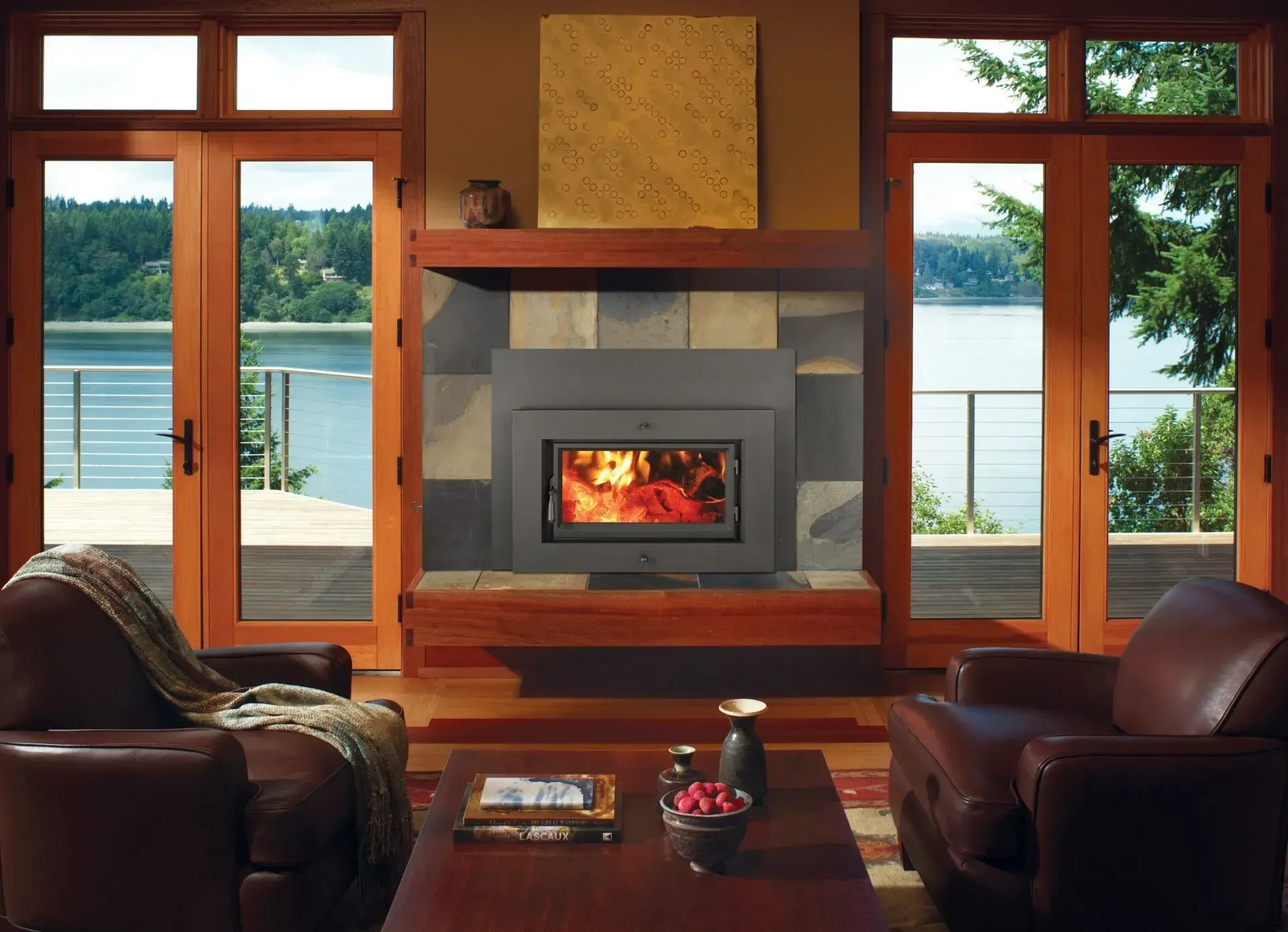 Cozy living room with fireplace, lake view, and two leather chairs.