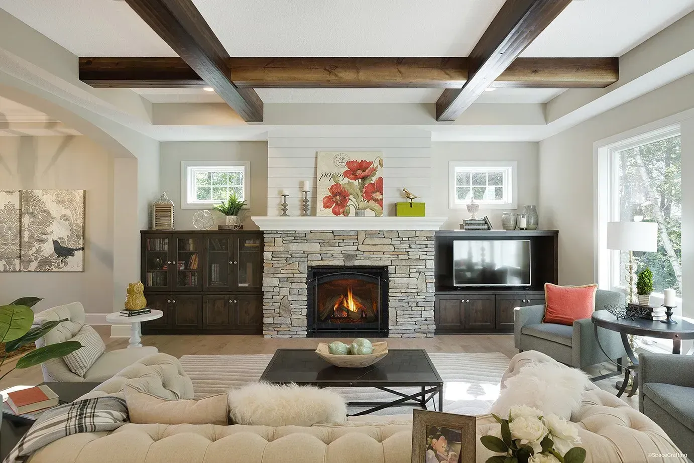 Living room with fireplace, stone hearth, wooden beams, and comfortable seating.