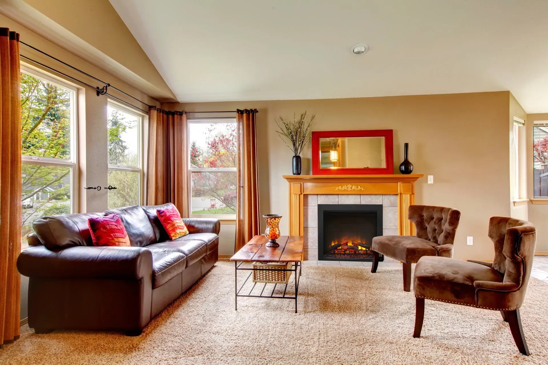 Living room with brown leather couch, fireplace, and two armchairs.