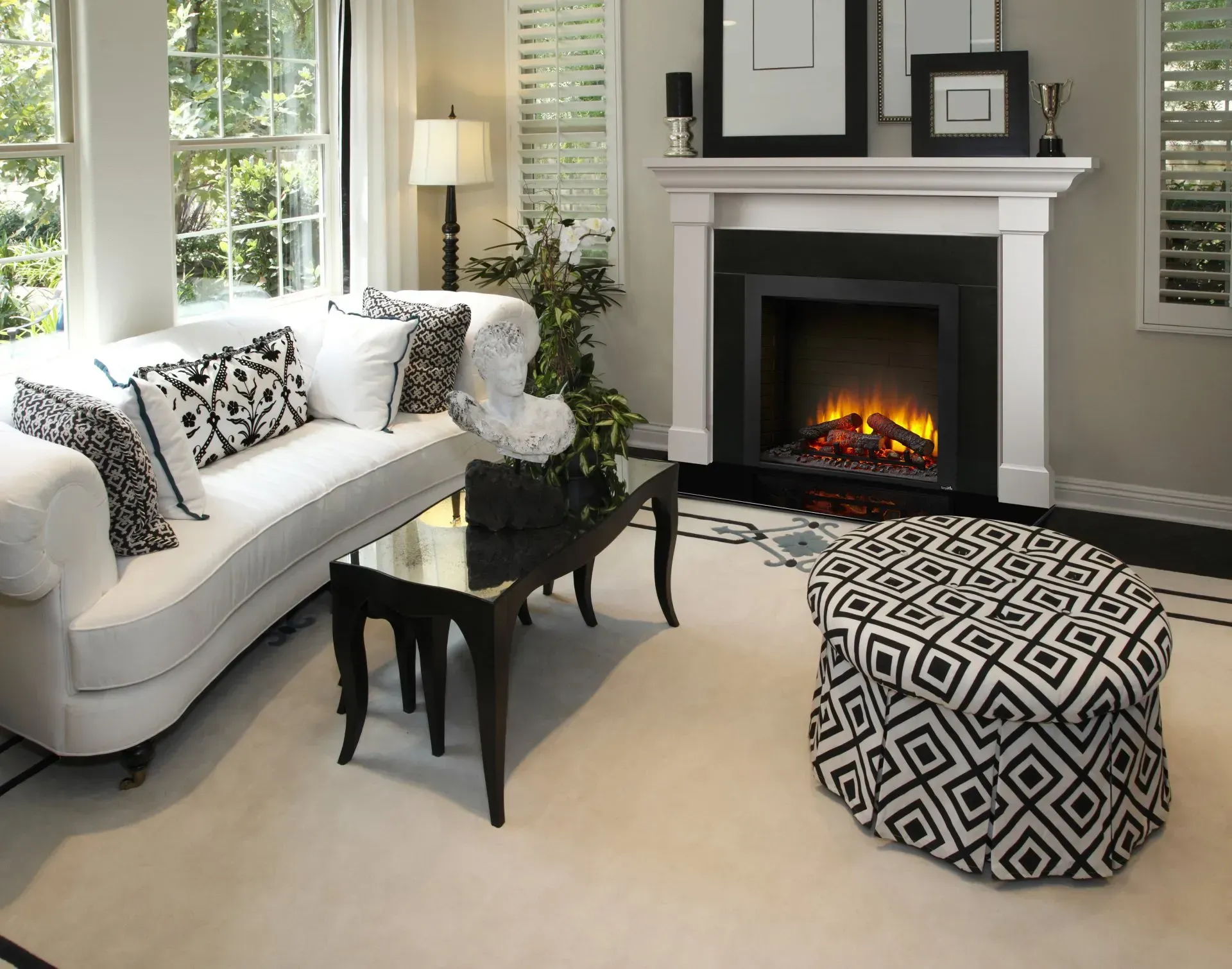 Living room with white sofa, fireplace, and patterned ottoman.