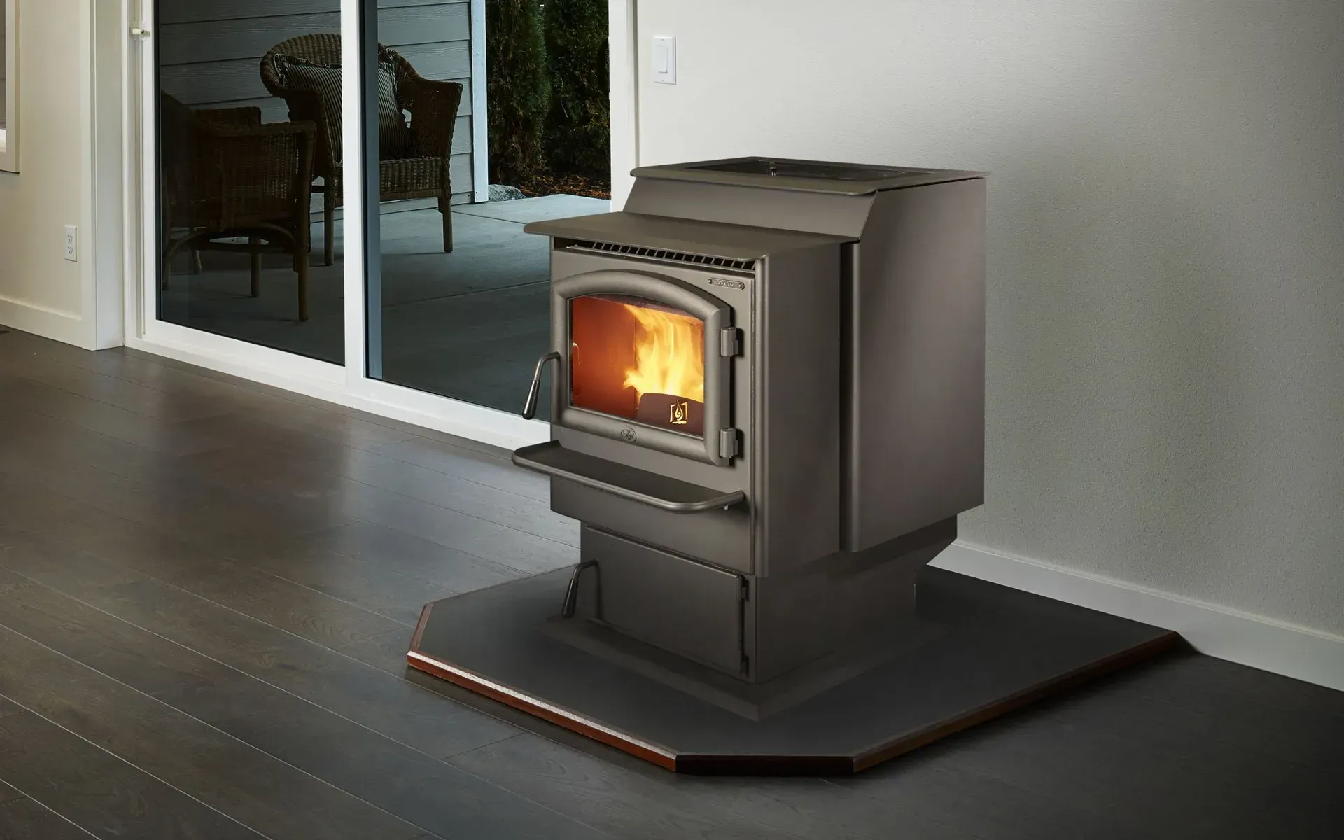 A brown pellet stove with a glowing fire, sitting on a black hearth, in a modern home.