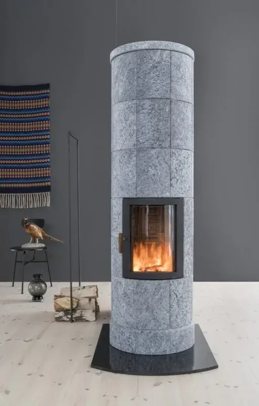 Tall, gray, stone fireplace with a glowing fire, in a modern room setting.