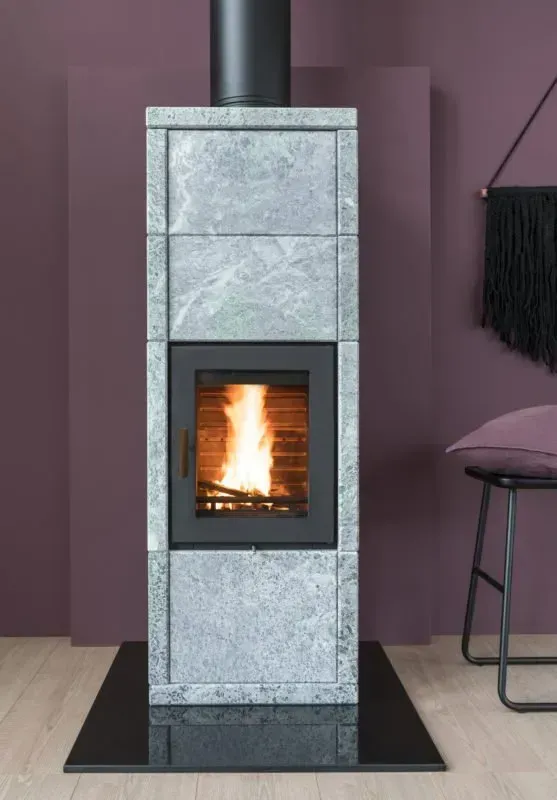 Stone fireplace with a burning fire, black chimney, set against a purple wall.