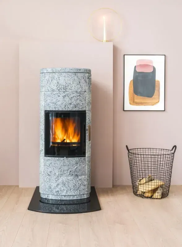 Fireplace with flames in a pink room, next to firewood basket and abstract art.