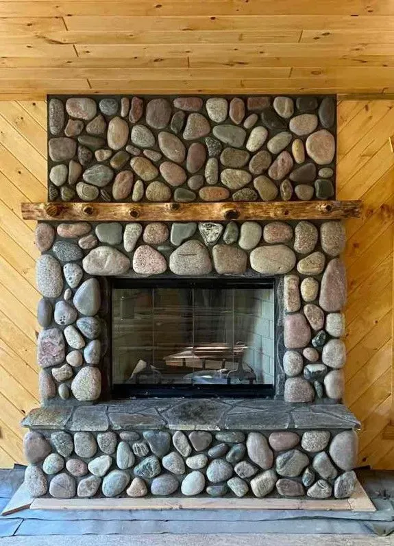 Stone fireplace with a wooden mantel and a fire inside.
