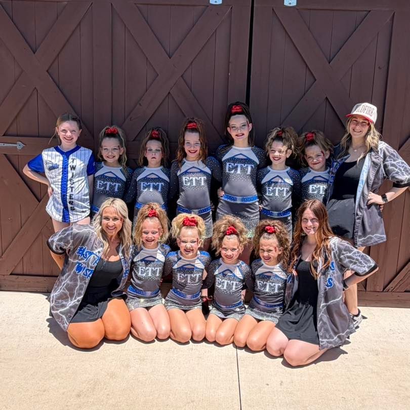 Cheer team group in black and silver uniforms posing in front of large wooden doors