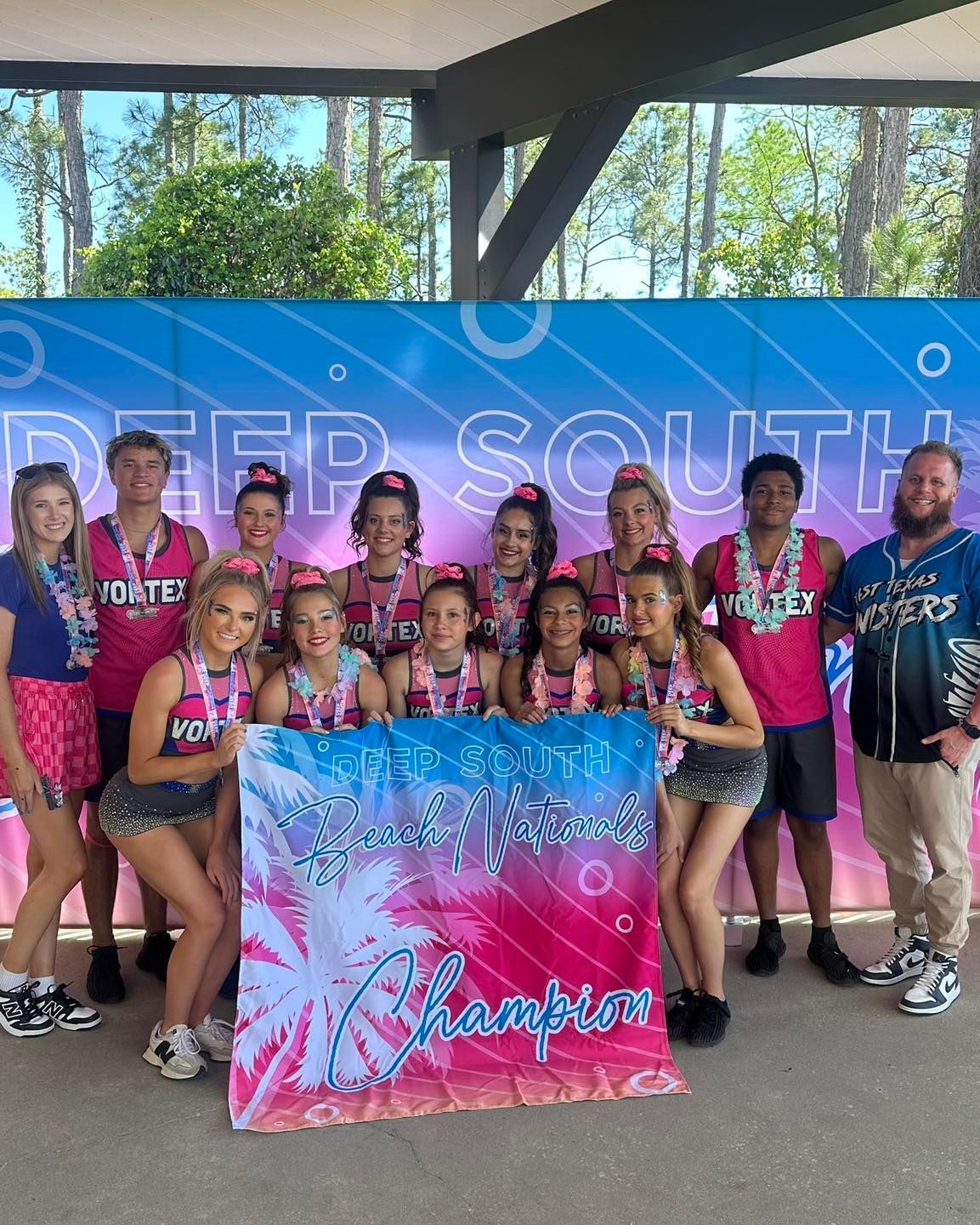 Youth cheer team posing with a “Champion” banner at an indoor awards celebration.