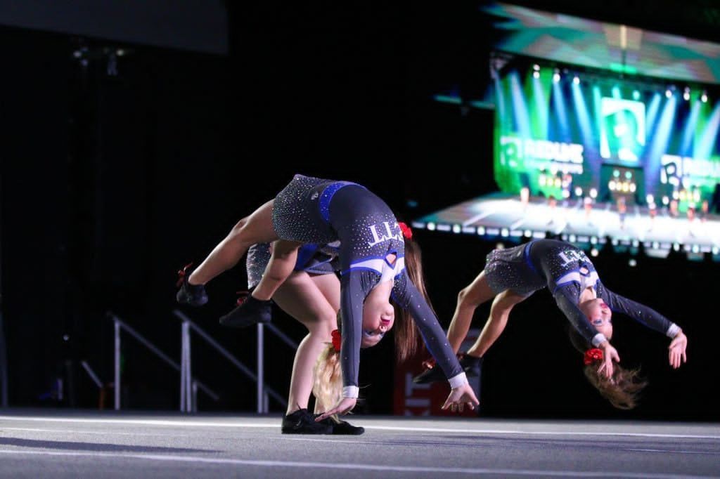 Gymnasts in blue leotards bending backward on a stage during a performance