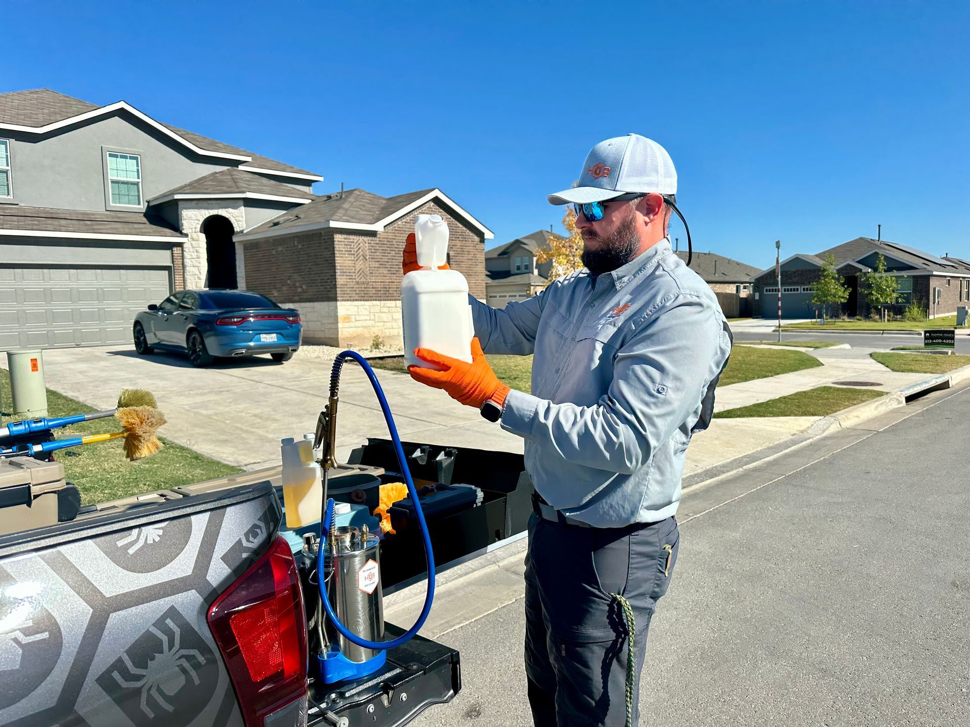 Man in uniform prepping pest control equipment in suburban setting.