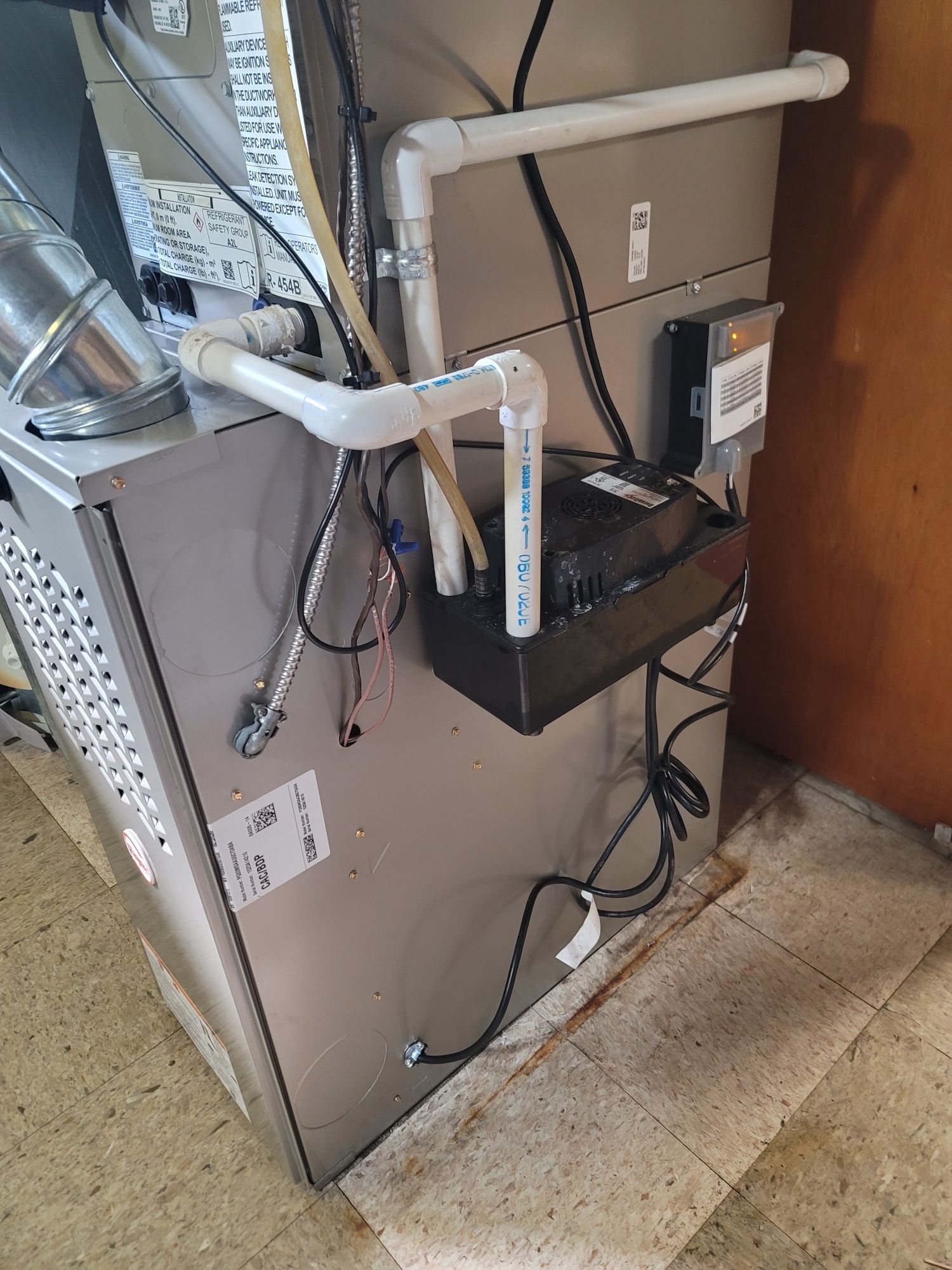 A furnace is sitting on the floor next to a wall.