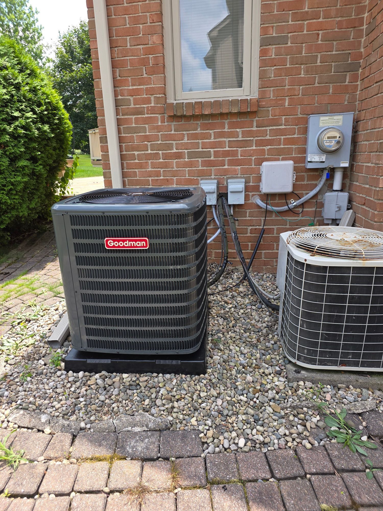An air conditioner is sitting on the side of a brick building.
