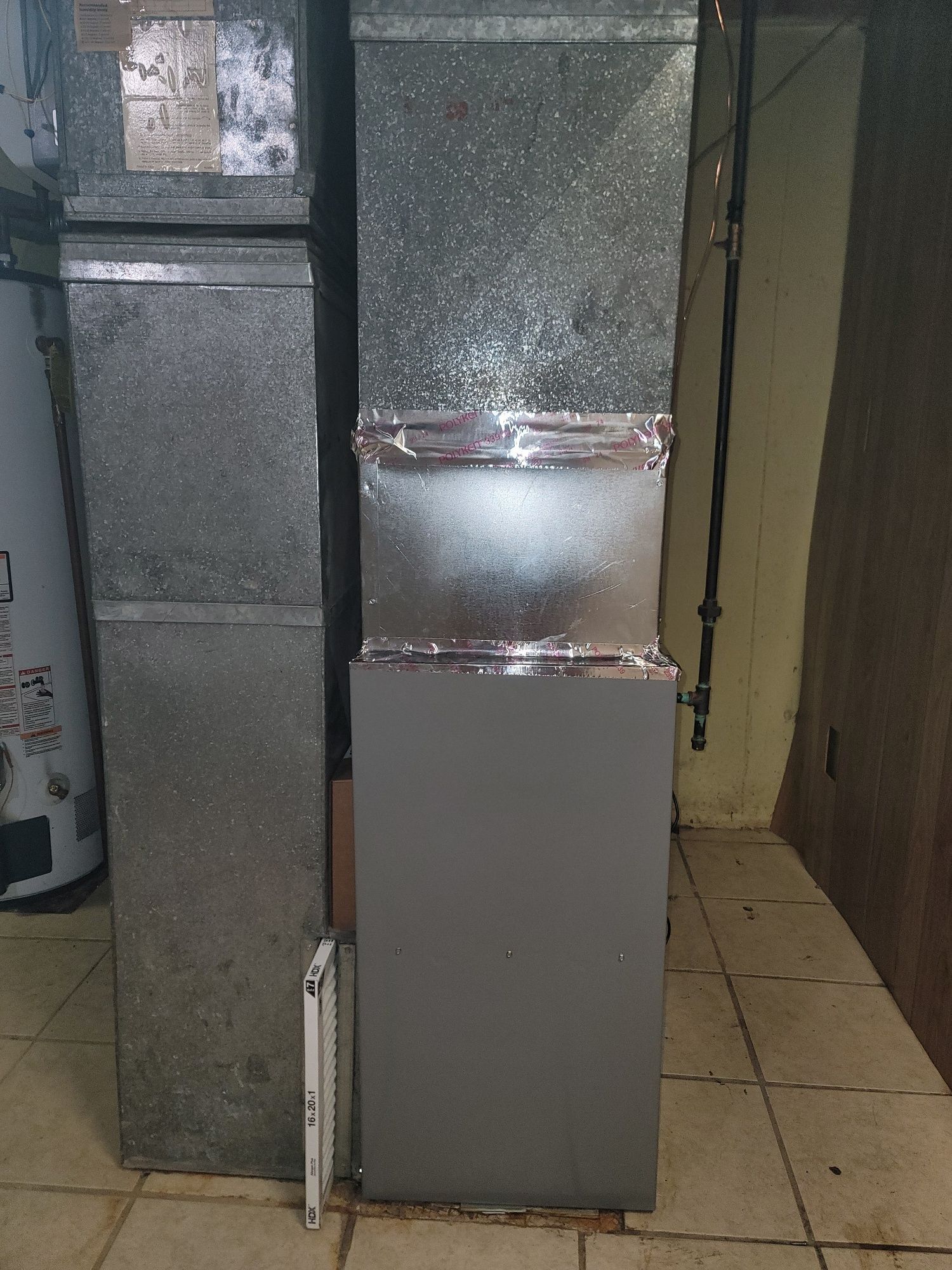 A refrigerator is sitting in a room next to a water heater.